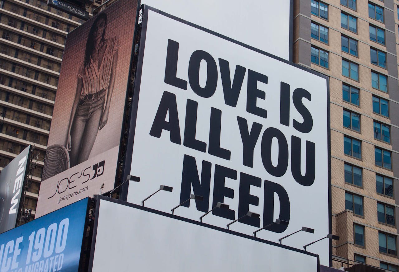gallery-05 Large city billboard reads 'Love Is All You Need' in New York City street.